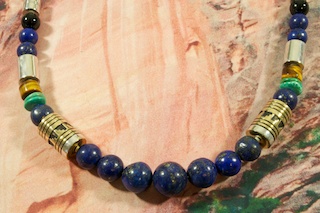 Genuine Blue Lapis with Accents of  Turquoise, Spiny Oyster Shell, Black Onyx and Tiger's Eye. Sterling Silver and Gold Filled Barrels. Sterling Silver Cones and Clasp. Created by Navajo Artist Tommy Singer. Signed by the artist.